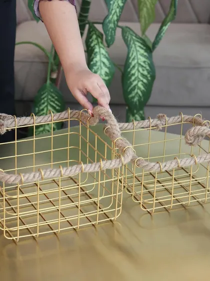 A pair of our gold wire and rope baskets, showing the two sizes available. They are perfect for creating a coordinated storage solution on a coffee table or shelf.
