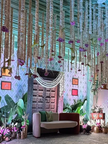 We designed this 'Southern Grace' baby shower entrance as a doorway to new life. The antique wooden door, traditional floral hangings, and lush greenery create a warm, inviting atmosphere rooted in cultural elegance.
