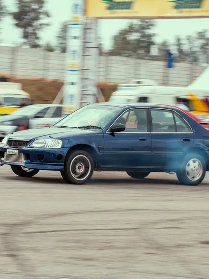 A blue modified Honda City, a classic in the Indian tuning scene, leaving a trail of tire smoke. The nostalgia and passion for these cars run deep in our community.