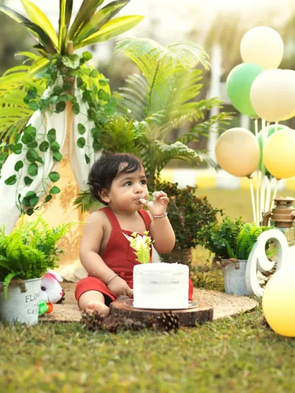 A moment of calm with the cake, surrounded by greenery and balloons. This outdoor setup combines nature with festive birthday elements.