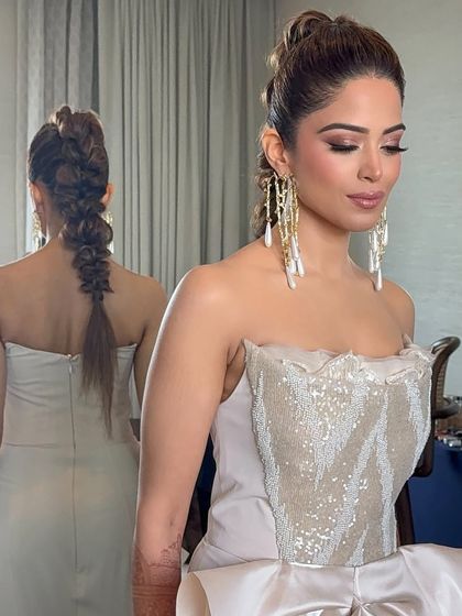 A sleek and chic pull-through braid, reflected in the mirror for a modern and edgy bridal look.