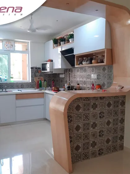 This stylish kitchen combines white cabinets with a curved, wood-laminate breakfast bar. The patterned tile on the bar front adds a decorative element, showing how we can mix classic materials with unique design touches.