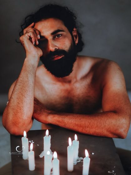 A raw and emotional portrait using the soft, flickering light of candles. The darkness reveals a sense of solitude and deep contemplation, where the gaze holds more than words ever could.