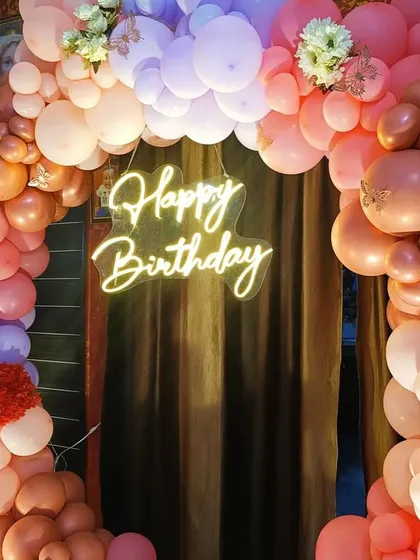 A second birthday party with a beautiful circular balloon arch in shades of pink, peach, and purple.