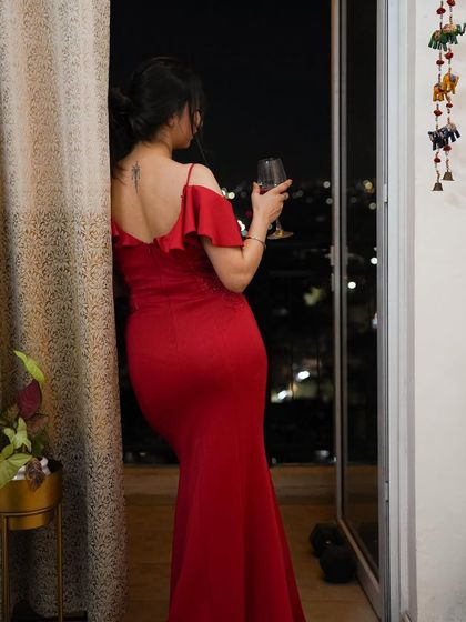 A candid moment with a glass of wine in the red gown, capturing a sophisticated and relaxed vibe.