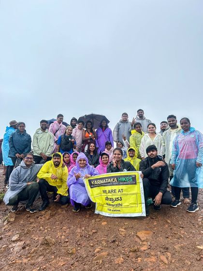 Another successful Netravathi trek. Our group in raincoats, celebrating at the summit with our banner.