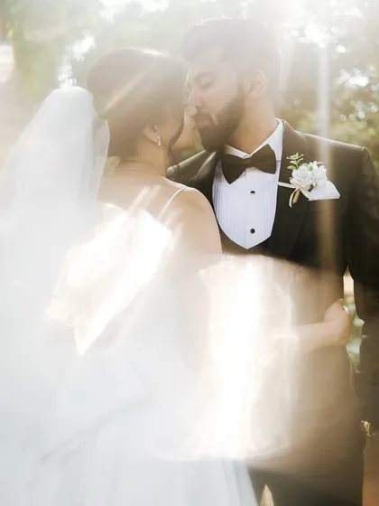 A dreamy, sun-flared portrait of the couple sharing an intimate moment, creating a soft and romantic effect.