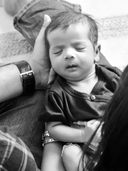 An intimate, over-the-shoulder view of parents admiring their sleeping baby. This black and white photo feels personal and candid, as if capturing a private family moment.