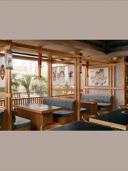 This wider view showcases the restaurant's layout, with its series of wooden-framed booths. The design creates semi-private zones for groups while maintaining a sense of openness and connection to the rest of the space.