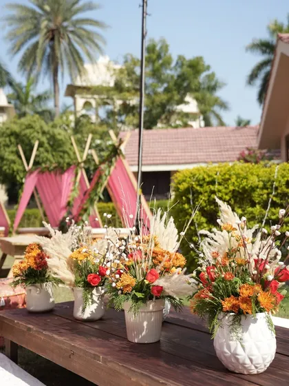 A collection of rustic table centerpieces, each with a unique combination of dried grasses and flowers. These details add to the overall boho-chic aesthetic of the event.
