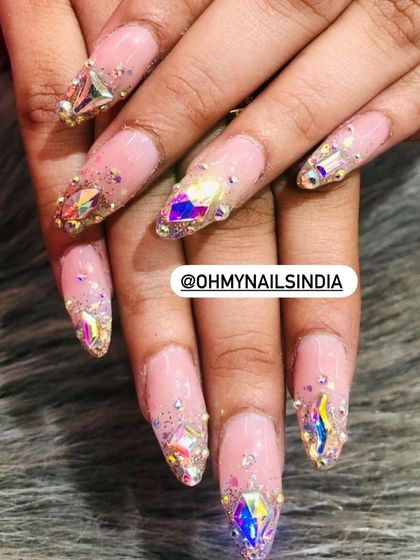Showcasing our skill in stone art. These nails are heavily embellished with large, iridescent crystals and smaller surrounding stones for a dazzling, jewel-like effect.
