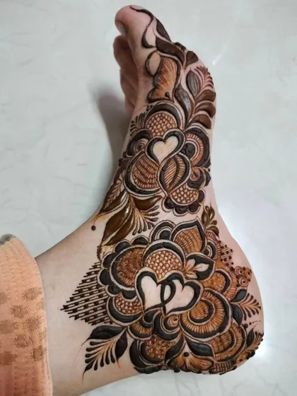 A romantic foot design featuring two hearts nestled within a beautiful floral pattern. A perfect way to add a personal touch to your bridal henna.