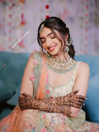 A serene bride with her eyes closed, as if making a wish. Her hands are covered in our beautiful bridal mehandi.