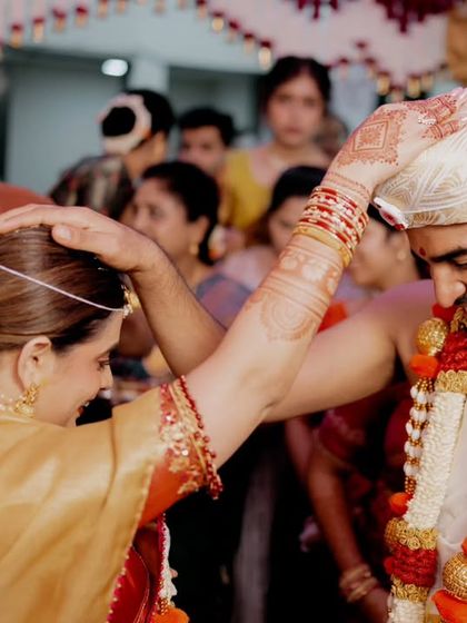 A tender moment where the bride blesses the groom. The gentle smile of the family member in the background adds another layer of emotion to the scene.