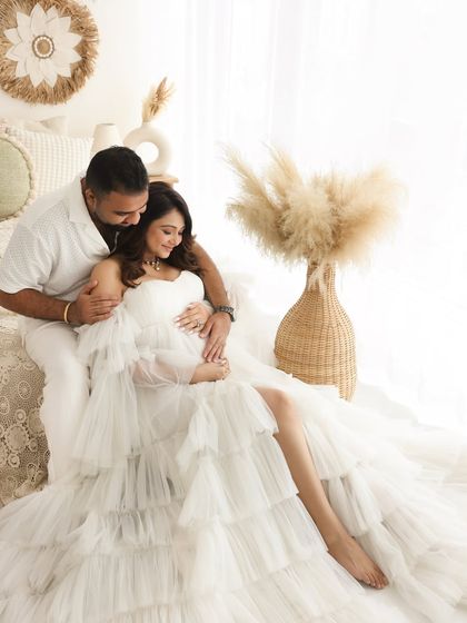 A cozy moment of intimacy. The contrast between the soft, ruffled white gown and the rustic, boho-inspired studio setup creates a unique and beautiful image.