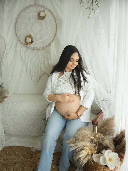 A chic and modern solo maternity portrait. The combination of a white blazer, crochet top, and jeans creates a stylish and contemporary look.