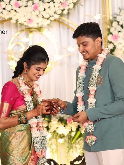 A sweet moment of the ring ceremony during an engagement, with an elegant floral and gold arch in the background.