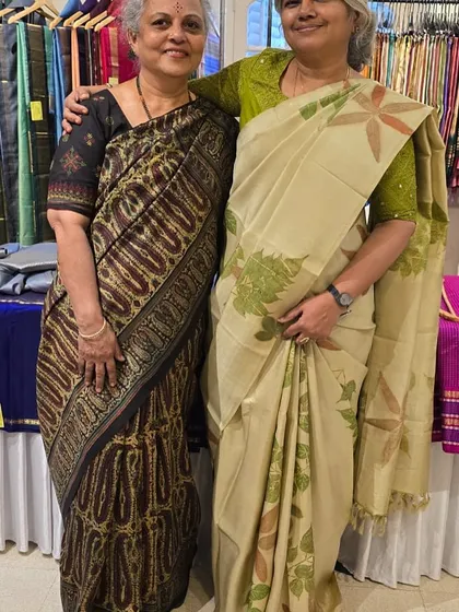 Posing with a friend at a textile exhibition. We are both wearing sarees that celebrate Indian craftsmanship.
