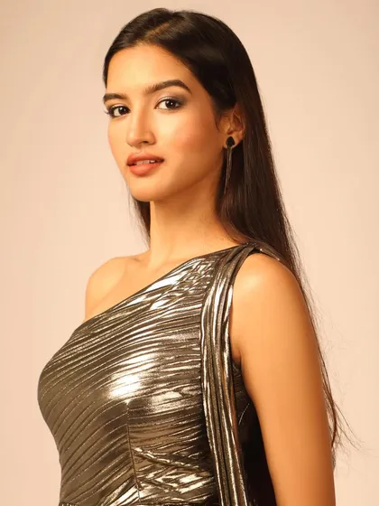 A close-up portrait that focuses on the model's expression and the texture of the one-shoulder dress.