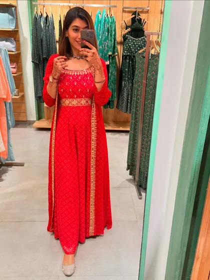 Another look at the red festive outfit, showing how it combines traditional embroidery with a modern silhouette.