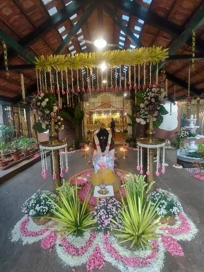 The central setup for the ceremony, featuring a beautiful floral rangoli made of fresh petals, traditional lamps, and arrangements of auspicious plants and flowers.