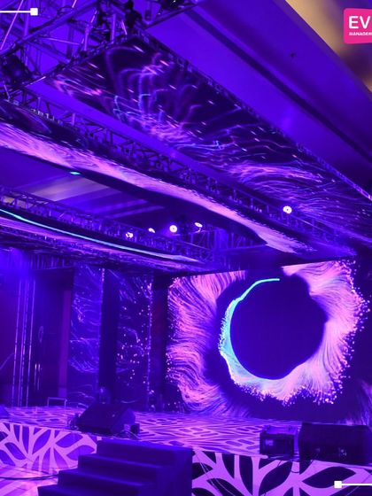 The Sangeet stage is bathed in dramatic purple light, with abstract visuals on the LED screen creating a dynamic and futuristic vibe. This setup is perfect for a high-energy night of music and dance.