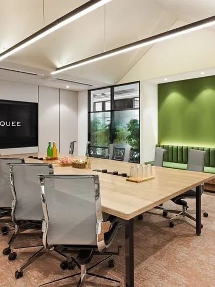 A conference room at CorporatEdge in Bangalore, designed with glass walls to promote transparency and collaboration. The space incorporates a green accent wall and biophilic elements, bringing a sense of calm and nature into the meeting environment.