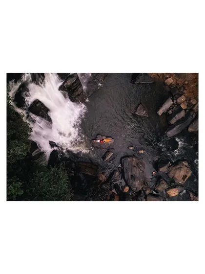 A stunning aerial drone shot of a couple relaxing by a waterfall, showcasing our ability to capture unique perspectives and epic scenery.