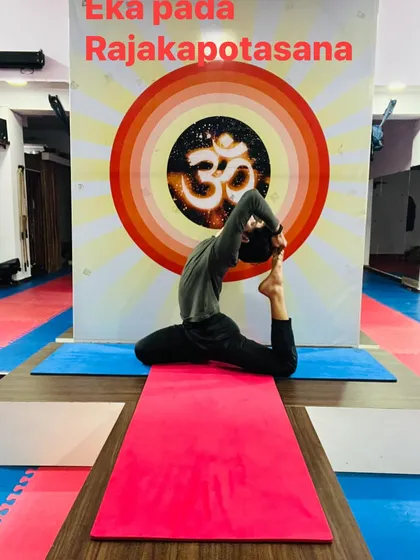 A solo practitioner in Eka Pada Rajakapotasana (One-Legged King Pigeon Pose). This deep stretch for the hips and spine is a goal for many students.