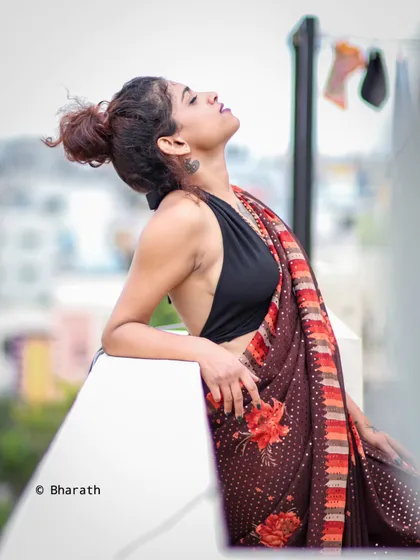 A modern and edgy interpretation of a saree, styled with a black halter top. Shot on a rooftop, this image has an urban, contemporary vibe.