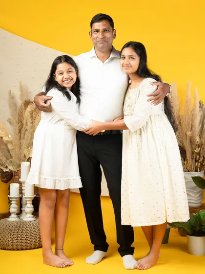 A father's embrace. His two daughters hug him tight, showing the strong and loving bond they share. This is a perfect photo for Father's Day or any day.