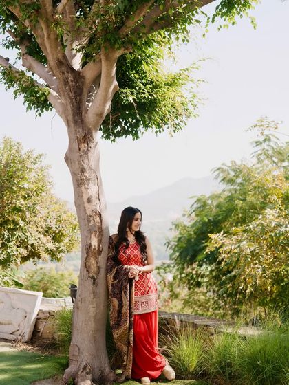 A smiling, relaxed pose in the red kurta set, showing a comfortable and graceful look.