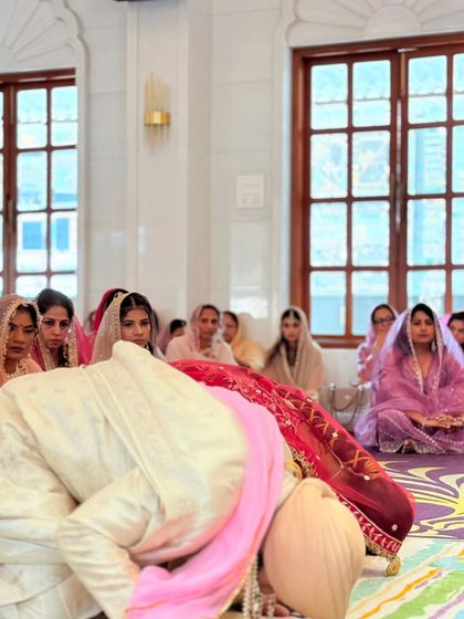 The bride and groom bow in respect during their Anand Karaj ceremony. This image captures the deep spiritual significance of the Sikh wedding vows.