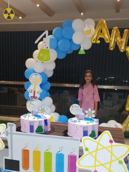 The birthday girl posing with her awesome Science themed party setup.