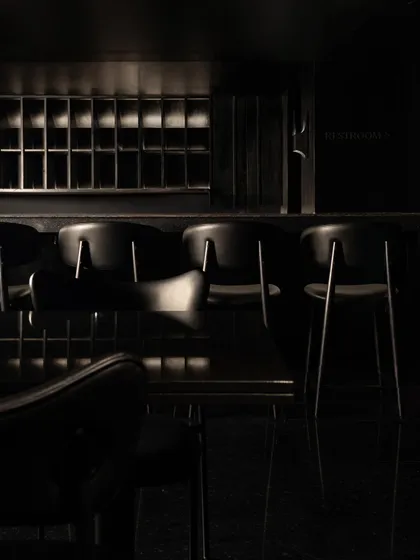 The bar seating, where the clean lines of the chairs stand out against the dark, textured backdrop.