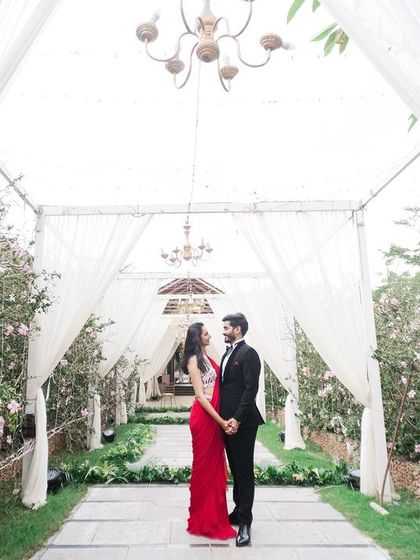 A duplicate of image 15, a breathtaking moment captured under a canopy of white drapes and chandeliers, creating a truly cinematic and romantic pre-wedding photograph.