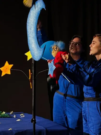 A close-up of the puppeteers from 'Volar Volar' interacting with the main puppet, Greta, and other celestial characters.
