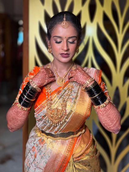 A moment of calm reflection. This image beautifully captures the bride's serene expression, showcasing the flawless makeup and the grandeur of her wedding necklaces.