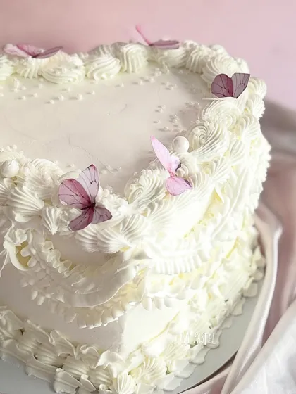 A big heart for a big love. This heart-shaped cake is decorated with vintage-style piping and delicate wafer paper butterflies. The flavor is a delicious Strawberry Baileys cream.