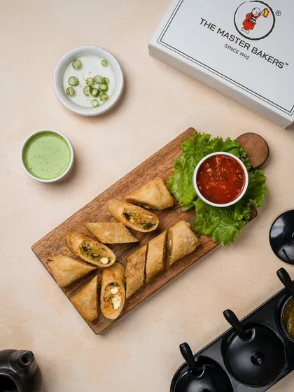 Our crispy vegetable spring rolls, sliced in half to show the fresh, colorful filling inside. They are served on a wooden board with a sweet chili dipping sauce.