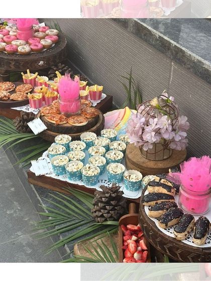 A close-up of the dessert section from a kids' party, with mini pizzas, donuts, eclairs, and popcorn cups, all arranged beautifully on rustic wooden platters.