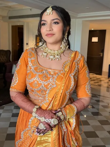 A portrait of the bride with her hair in a soft, wavy half-updo for her Haldi ceremony. The style is elegant and keeps the hair neatly away from her face.