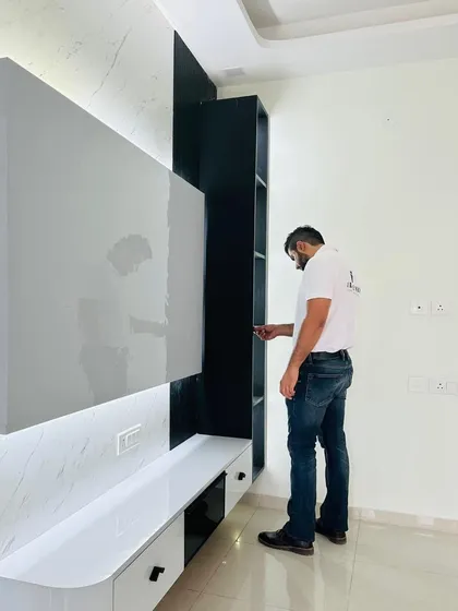 A close-up of a modern TV unit with a high-gloss white finish and a marble-patterned back panel. The unit includes both drawers and open shelving for versatile storage.