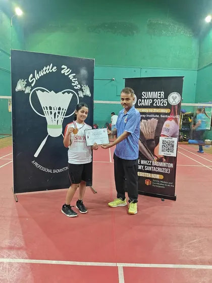 This young athlete proudly shows off her medal and certificate from the summer camp. We celebrate every step of a player's development journey.