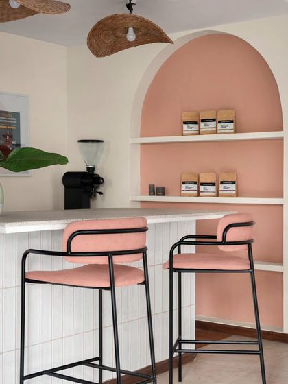 A detail shot of the island counter and display arch at Kana Cafe. The peach accent wall and custom furniture create a warm and stylish corner for merchandising and events.