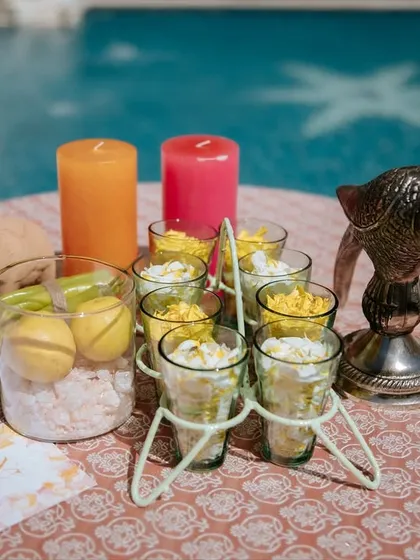 A poolside table setting for the 'Nazar na lage' lunch, with colorful candles and decor elements that tie into the theme. The water in the background adds to the serene atmosphere.