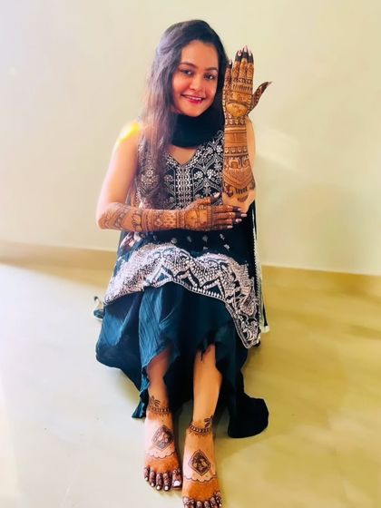 A client showing her complete look, with beautiful mehandi on her hands and feet.