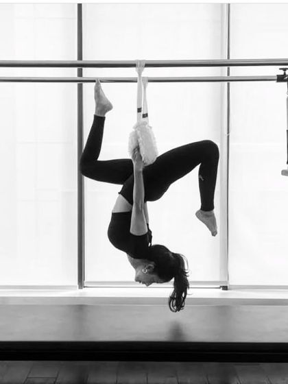A black and white shot of a hanging inversion on the Cadillac. This move is not only a great workout but also feels incredibly restorative for the spine.