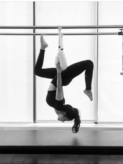 A black and white shot of a hanging inversion on the Cadillac. This move is not only a great workout but also feels incredibly restorative for the spine.