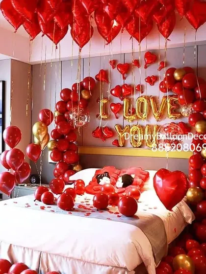 A classic and full romantic bedroom setup. The decoration features a balloon arch over the bed, 'I LOVE YOU' foil letters, and a ceiling full of red heart-shaped balloons, leaving no doubt about the message.